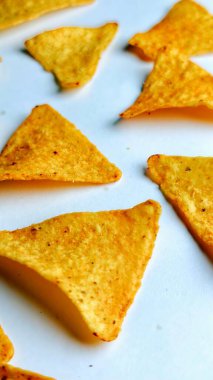 Çıtır altın üçgenli mısır cipsleri temiz beyaz arka planda kapanıyor çıtır çıtır bir doku, lezzetli baharatlar ve yiyecek markalaştırma, reklam ve ticari kullanım için mükemmel atıştırmalıklar sunuyor..