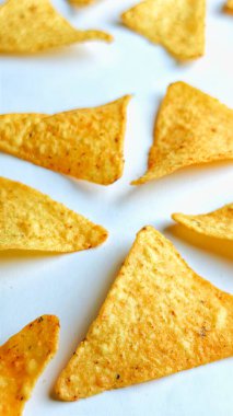 Çıtır altın üçgenli mısır cipsleri temiz beyaz arka planda kapanıyor çıtır çıtır bir doku, lezzetli baharatlar ve yiyecek markalaştırma, reklam ve ticari kullanım için mükemmel atıştırmalıklar sunuyor..