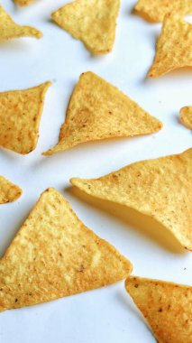 Çıtır altın üçgenli mısır cipsleri temiz beyaz arka planda kapanıyor çıtır çıtır bir doku, lezzetli baharatlar ve yiyecek markalaştırma, reklam ve ticari kullanım için mükemmel atıştırmalıklar sunuyor..