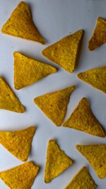 Çıtır altın üçgenli mısır cipsleri temiz beyaz arka planda kapanıyor çıtır çıtır bir doku, lezzetli baharatlar ve yiyecek markalaştırma, reklam ve ticari kullanım için mükemmel atıştırmalıklar sunuyor..