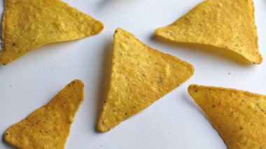 Çıtır altın üçgenli mısır cipsleri temiz beyaz arka planda kapanıyor çıtır çıtır bir doku, lezzetli baharatlar ve yiyecek markalaştırma, reklam ve ticari kullanım için mükemmel atıştırmalıklar sunuyor..