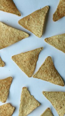 Çıtır altın üçgenli mısır cipsleri temiz beyaz arka planda kapanıyor çıtır çıtır bir doku, lezzetli baharatlar ve yiyecek markalaştırma, reklam ve ticari kullanım için mükemmel atıştırmalıklar sunuyor..