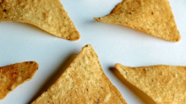 Çıtır altın üçgenli mısır cipsleri temiz beyaz arka planda kapanıyor çıtır çıtır bir doku, lezzetli baharatlar ve yiyecek markalaştırma, reklam ve ticari kullanım için mükemmel atıştırmalıklar sunuyor..