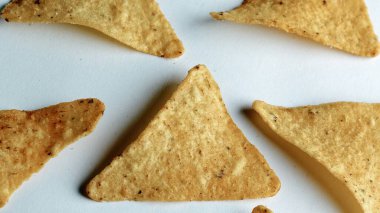 Çıtır altın üçgenli mısır cipsleri temiz beyaz arka planda kapanıyor çıtır çıtır bir doku, lezzetli baharatlar ve yiyecek markalaştırma, reklam ve ticari kullanım için mükemmel atıştırmalıklar sunuyor..