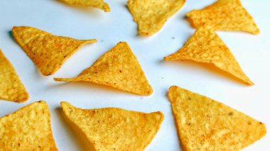 Çıtır altın üçgenli mısır cipsleri temiz beyaz arka planda kapanıyor çıtır çıtır bir doku, lezzetli baharatlar ve yiyecek markalaştırma, reklam ve ticari kullanım için mükemmel atıştırmalıklar sunuyor..