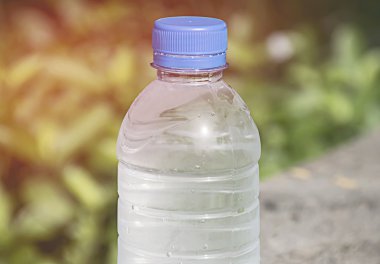 Su şişesi üzerinde doğa arka plan ile ahşap masa. 