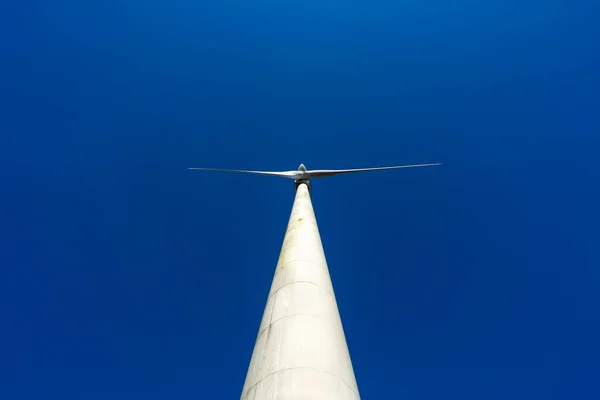 Άποψη από τα κάτω των αιολικών και ανανεώσιμων πηγών ενέργειας masts με μεγάλες έλικες και τουρμπίνες τους σε μια αγροτική περιοχή στη βόρεια Ισπανία. Έννοια εναλλακτικής και ανανεώσιμης ενέργειας. — Φωτογραφία Αρχείου