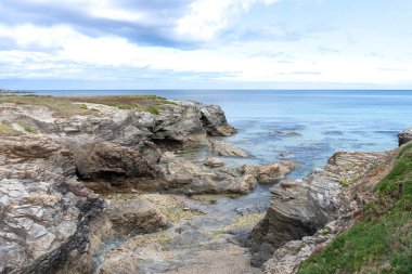Kuzey İspanya 'daki Las Catedrales' in sakin sahillerinde bulutlar ve dev taşlarla dolu güzel mavi bir gökyüzü..