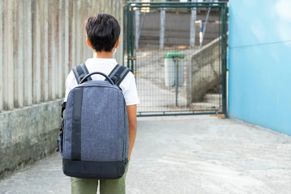 Um menino de costas para a escola olha para a entrada da escola com sua mochila pronta para o início do ano letivo. Voltar ao conceito de escola — Fotografia de Stock