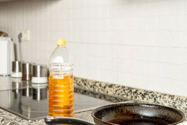 Plastflaska med återvunnen ätlig olja bredvid stekpanna i köket i ett hus. Återvinningskoncept i hemmet — Stockfoto