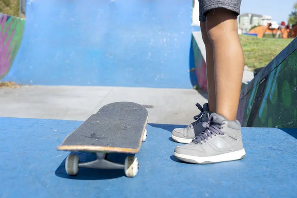 Close up de pernas de uma criança em um skate prestes a começar a desfrutar de um parque de skatistas — Fotografia de Stock