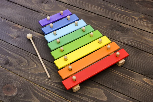 Xylophone di meja kayu cokelat tua. xylophone anak-anak, dicat dengan warna pelangi . — Stok Foto