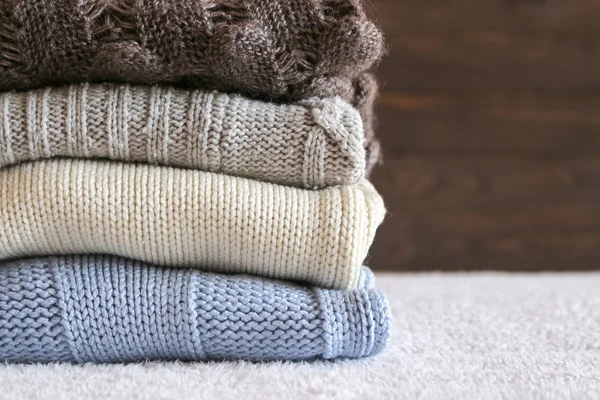 Stack of cozy knitted warm sweater on your home background . Sweaters in retro Style. The concept of warm .