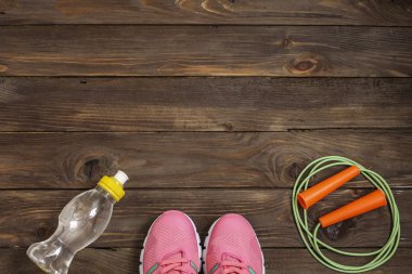 Spor ayakkabı, ip ve su şişesi üzerinde ahşap arka plan atlama. Spor, beslenme ve sağlıklı yaşam konsepti. Fitness için giyim ve Spor aksesuarları. Üstten Görünüm. Reklam için yer.