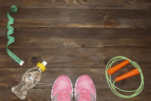 Sportschoenen, touw en waterfles overslaan op houten achtergrond. Sport, voeding en gezonde levensstijl concept. Kleding en sport accessoires voor fitness. Het uitzicht vanaf de top. De plek om te adverteren. — Stockfoto