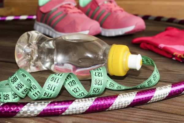 Sports apparel, skipping rope, hula Hoop, bottle of water and tape measure on wooden background .Sport, diet, exercises and healthy lifestyle concept. Clothing and accessories for fitness, gymnastics. — ストック写真