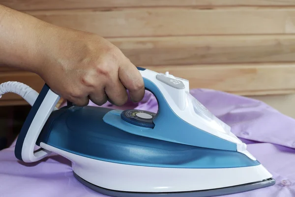 Hierro. Planchado de la camisa de limpieza de vapor con la plancha.Mano femenina. La herramienta eléctrica . —  Fotos de Stock