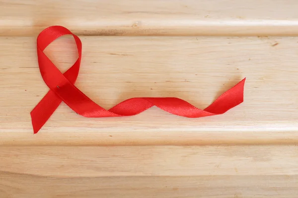 De symbolische voorstelling van de Werelddag voor Aids-bestrijding. Symbolische rood lint op houten achtergrond. — Stockfoto