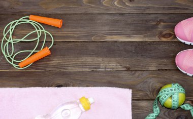 Giysi, nesneleri, spor için aksesuarlar. Koşu ayakkabıları, atlama ipi, havlu, teyp ve su şişesi ölçme bir elma. Ahşap arka plan ekipman. Sağlıklı beslenme. Reklam için yer.