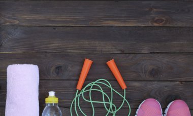 Spor ayakkabı, ip ve su şişesi üzerinde ahşap arka plan atlama. Spor, beslenme ve sağlıklı yaşam konsepti. Fitness için giyim ve Spor aksesuarları. Üstten Görünüm. Reklam için yer.