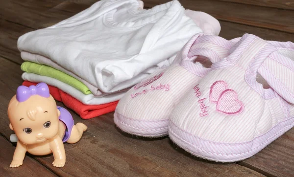 Kit para recién nacidos. Ropa de bebé y botines sobre fondo de madera  . —  Fotos de Stock