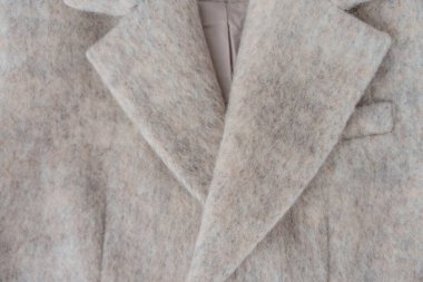 Yumuşak tüylü yüzeyi olan, doğal bej renkte yün karışımı ceketin makro görüntüsü. Moda, kumaş dokusu veya dış giyim tasarımları için klapa tasması ayrıntıları