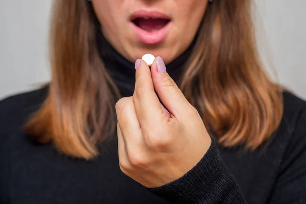 年轻的女人吃避孕药 女人服用药物 抗抑郁药或避孕药 女人把药片放进嘴里有止痛药或抗生素 带有药物的保健概念 — 图库照片