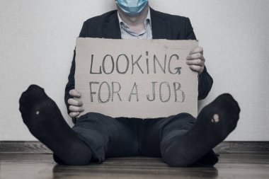 Karantina yüzünden işini kaybeden genç bir işadamı iş arıyor. Tıbbi maskeli bir işadamı elinde karton bir levhayla yerde oturuyor ve iş arıyor. İşsizlik büyümesi kavramı