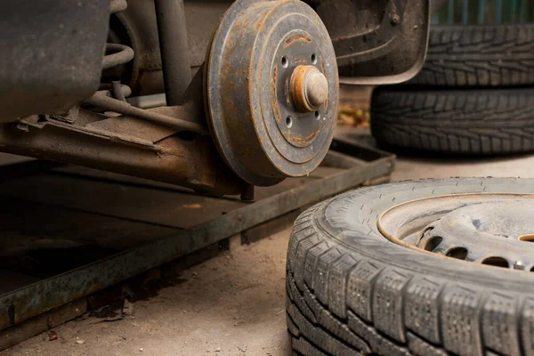 Car on tire mounting with removed wheel. Wheel hub closeup. Seasonal tire change. Empty rusty hub without wheel. Car service concept.