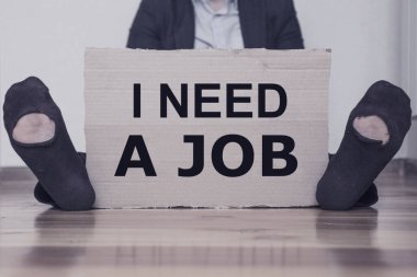 Üzerinde yazı olan bir karton tutan bir adam. Bir işe ihtiyacım var. İş arama kavramı, azaltma. Kilitleme sırasında işsizlik artışı kavramı.