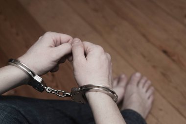 Kelepçeli bir adam. Tutuklu ya da kelepçeli bir adam. Elleri kelepçeli bir erkek. Ceza hukuku.