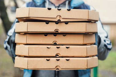 Pizza getiren bir adam. Bir kurye büyük bir pizza kutusunu tutuyor. Pizza teslimatçısı bir eve pizza getiriyor..