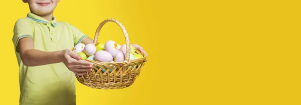 Małe Dziecko Trzyma Koszyk Pomalowanymi Jajkami Żółtym Tle Dzień Wielkanocny — Zdjęcie stockowe
