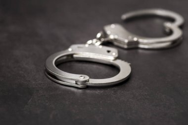 Siyah arka plandaki metal kelepçeler. Kelepçe mi kelepçe mi? Polis kelepçesi..