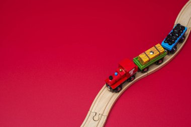 Kırmızı zemin üzerinde demiryolu üzerinde tahta oyuncak tren. Anaokulu ve anaokulu çocuğu için eğitici oyuncaklar. Metin için alanı kopyala.