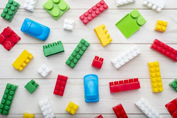 Colorful plastic toy blocks. Colorful plastic toy blocks on white wooden background. Top view. Baby background