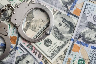 Para geçmişinde kelepçe. Dolar banknotları, para, yolsuzluk, kara para, mali suç ve metal polis kelepçeleri..