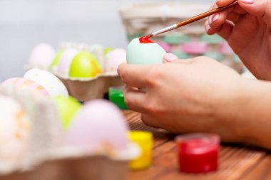 Püsküllü bir kadın Paskalya yumurtalarını boyuyor. Paskalya için dekorasyon hazırlamak, çocuklarla yaratıcılık, geleneksel semboller. Paskalya için hazırlanılıyor.