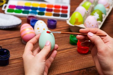 Püsküllü bir kadın Paskalya yumurtalarını boyuyor. Paskalya için dekorasyon hazırlamak, çocuklarla yaratıcılık, geleneksel semboller. Paskalya için hazırlanılıyor.