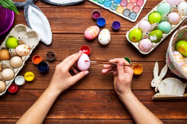 Püsküllü bir kadın Paskalya yumurtalarını boyuyor. Paskalya için dekorasyon hazırlamak, çocuklarla yaratıcılık, geleneksel semboller. Paskalya için hazırlanılıyor.