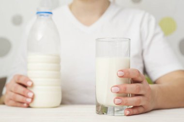Elinde bir bardak sütle beyaz bir tahta masada oturan bir kadın. Sağlıklı beslenme. Sağlıklı yaşam tarzı.