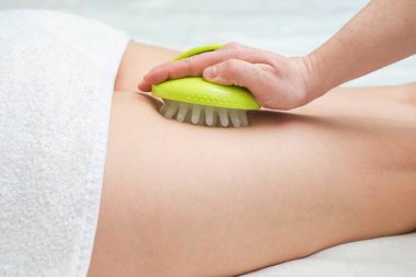 Masör, masaj karşıtı genç bir kadın yapıyor. Selüliti önlemek için masaj aleti ile masaj yap.