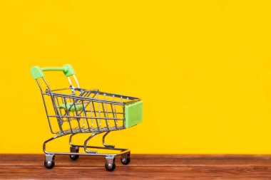 Sarı arka planda alışveriş arabası. Alışveriş konsepti. Reklam için boşluk kopyala.