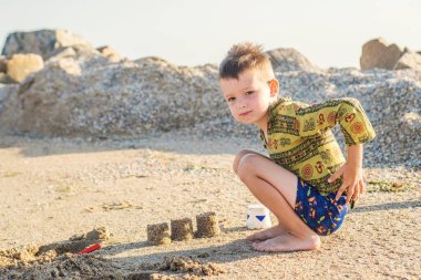 Çocuk yaz tatilinde plajda oynuyor. Çocuk kumsalda kumla oynuyor..