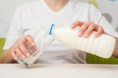 Evdeki mutfakta sütü olan genç bir kadın. Kadın mutfakta süt içiyor..