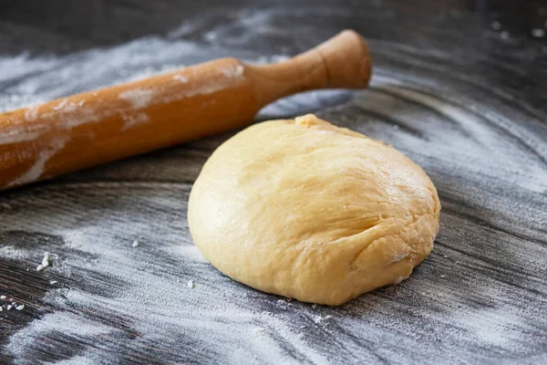 Taze hamur pişmeye hazır. Ahşap mutfak tezgahında merdaneli ekmek hamuru.