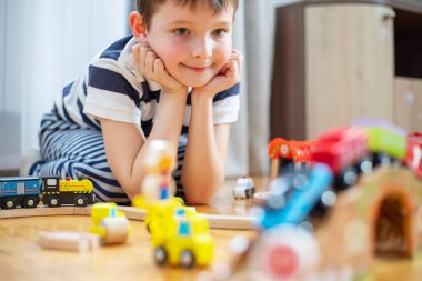 Sevimli çocuk evde ya da yerde oyuncak tren yolu ile ya da anaokulunda oynuyor. Çocuk evde ya da anaokulunda.