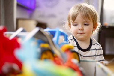 Oyuncak çocuğun önünde bir sürü farklı ve renkli oyuncak. Küçük çocuk çocuk odasında oyuncak oynuyor..