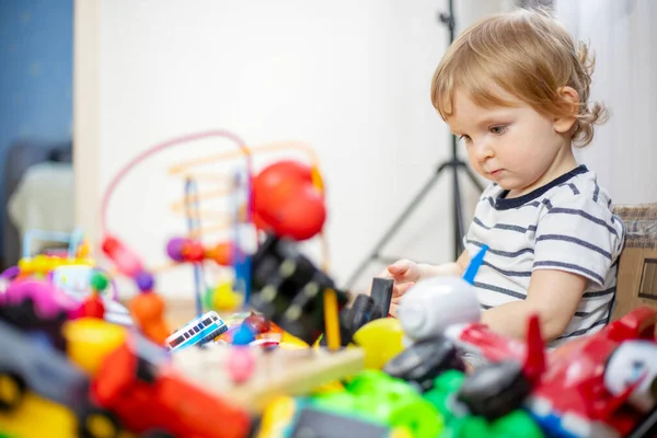 Oyuncak çocuğun önünde bir sürü farklı ve renkli oyuncak. Küçük çocuk çocuk odasında oyuncak oynuyor..