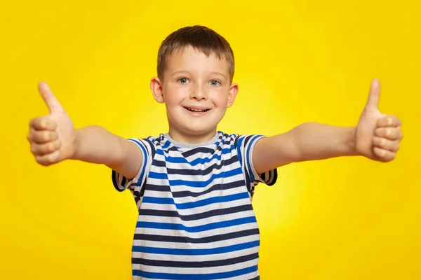 穿着条纹T恤衫的快乐男孩的画像 在黄色背景下露出大拇指的姿势 — 图库照片